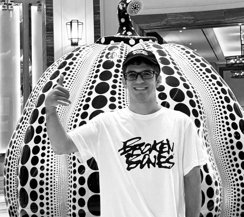 Person wearing a white t-shirt with black text in front of a large, patterned sculpture.